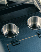 Two metal cup holders on a black textured surface
