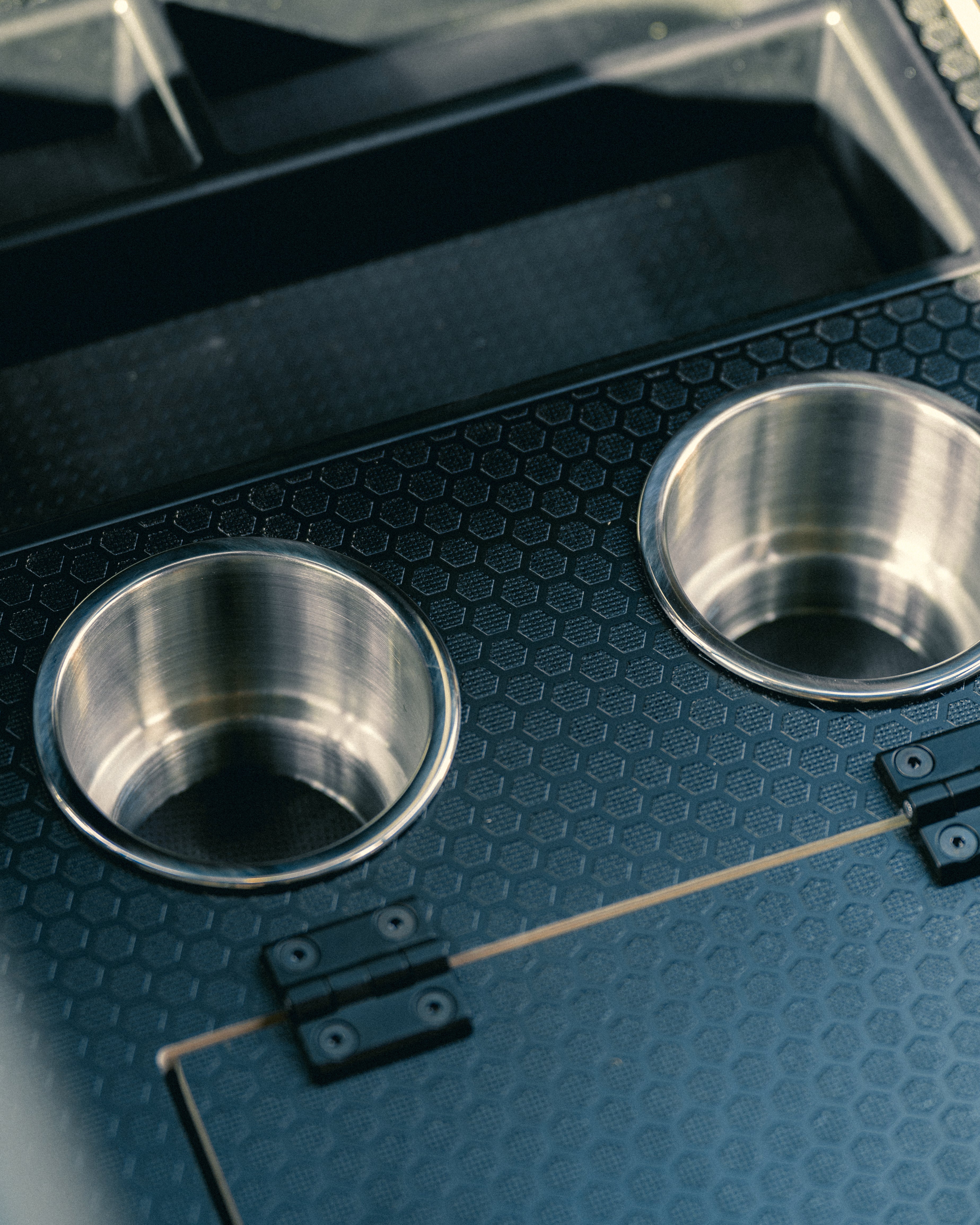 Two metal cup holders on a black textured surface